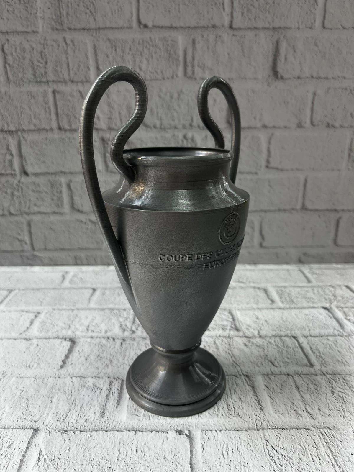 Fume Kupa 25cm Uefa Model Dekoratif Odul Biblosu 363704613 Sw1200sh1600 700x933 Füme Kupa 25cm UEFA Model Dekoratif Ödül Biblosu najmaddin.com UEFA Şampiyonlar Ligi kupasından ilham alınarak tasarlanmış şık ve premium bir dekoratif objedir. Mat füme tonu ve detaylı gövde yapısı ile spor temalı koleksiyonlarında özel bir yere sahip olur. Hafif fakat dengeli yapısıyla masa
